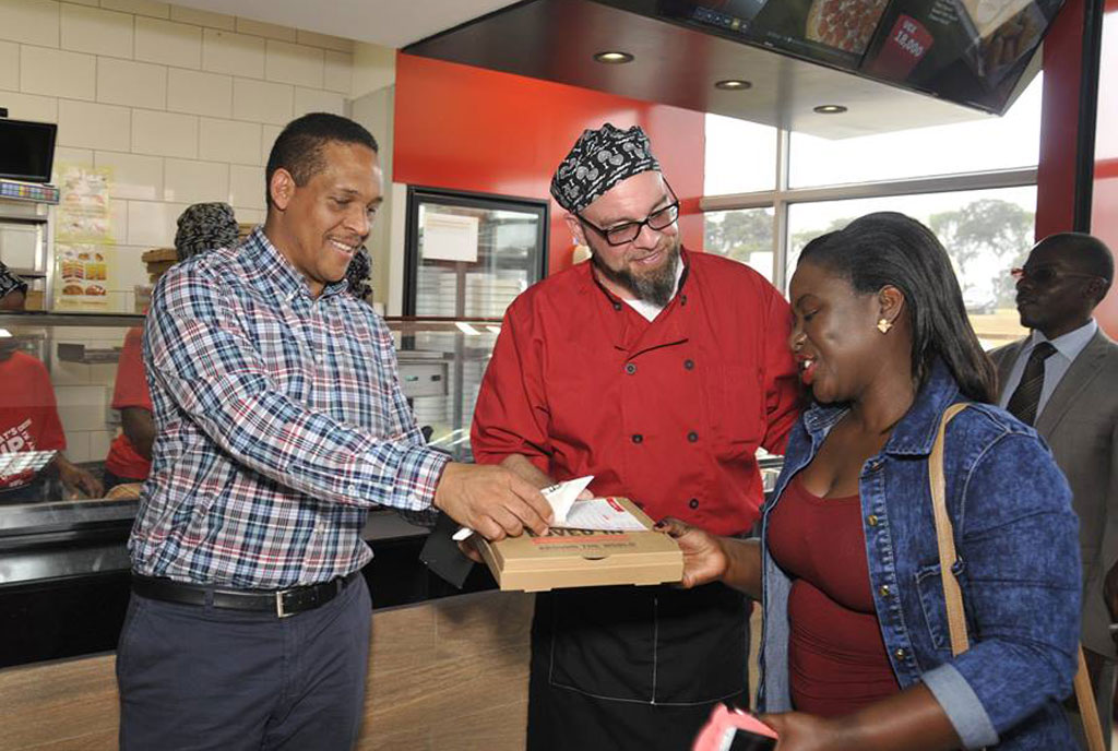 Hans Paulsen (right) hands a pizza to an invited guest at the launch of Pizza Hut in Entebbe. PHOTO BY lawrence ogwal
